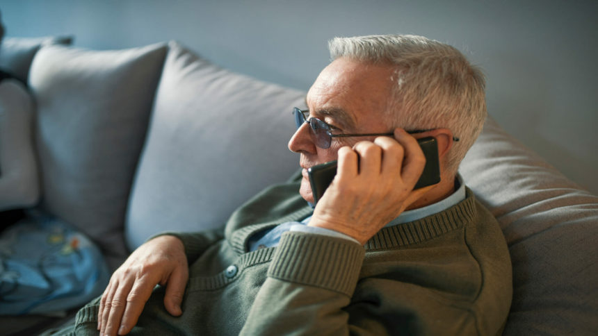 Older man sitting on couch talking on the phone