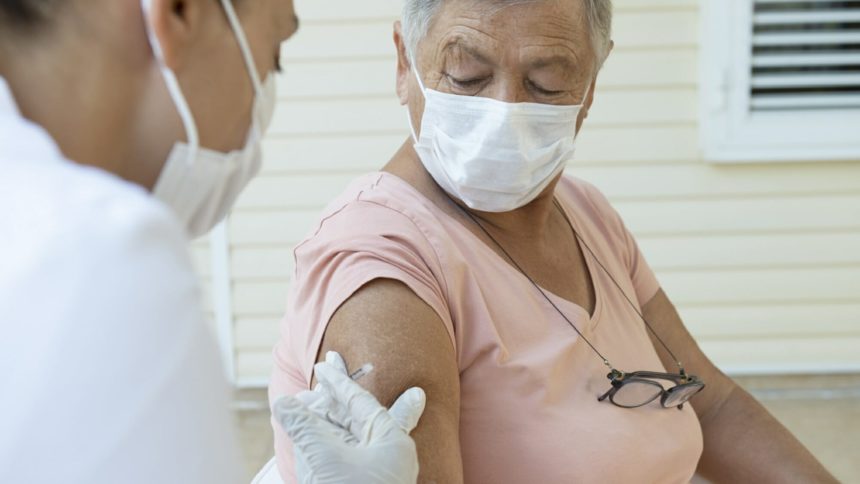 older woman about to get a shot from a healthcare worker