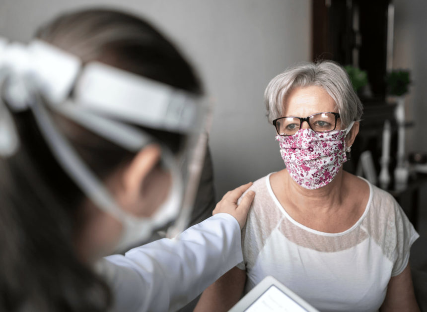 woman in face shield with hand on shoulder of other woman