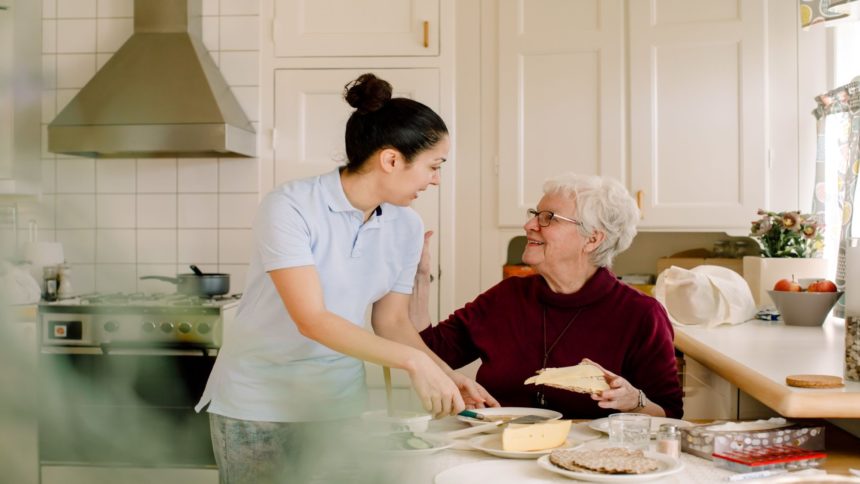 Elderly woman in kitchen with her caretaker