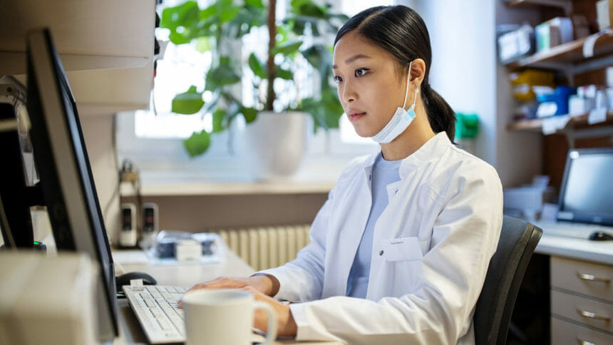 Serious-looking healthcare professional looks at computer in office