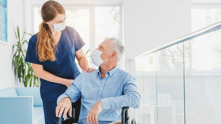 Caregiver looks at senior man in wheelchair