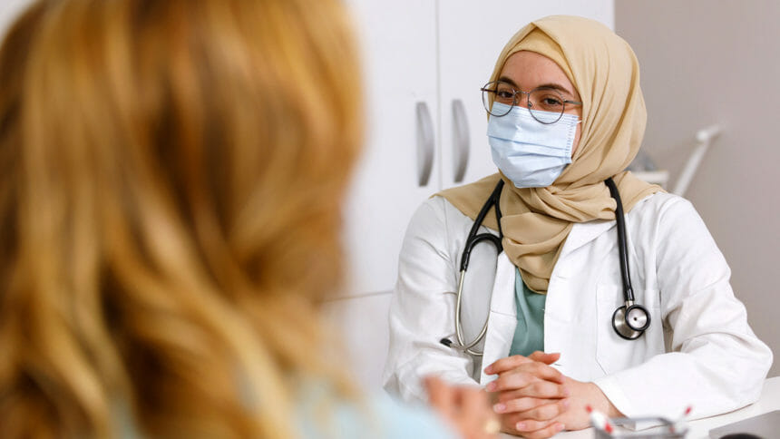 Moslem doctor wearing stethoscope talks to patient