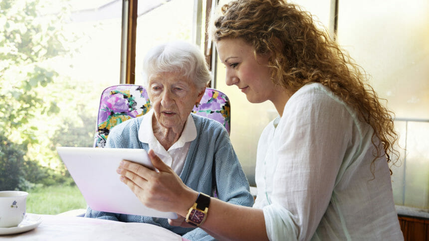 Young woman shows older woman tablet