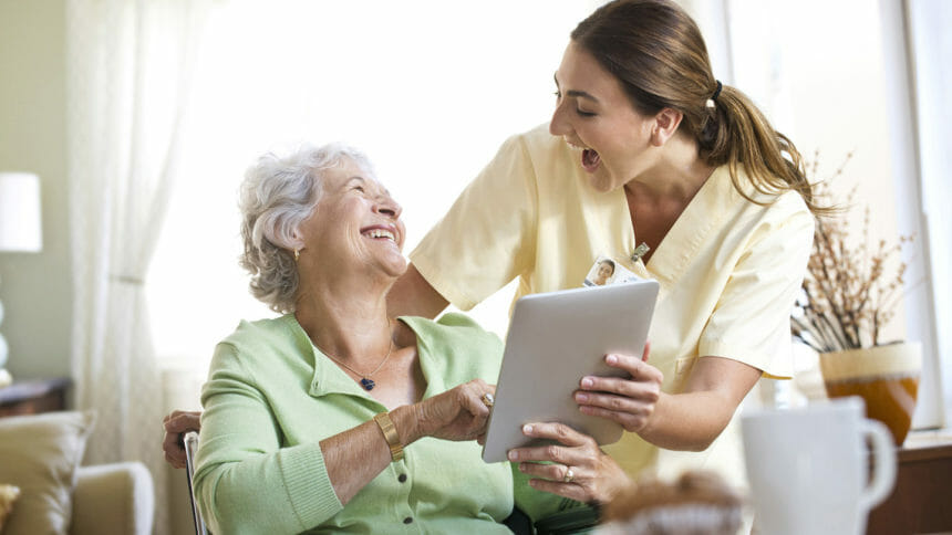 Caregiver and senior enjoy each other's company as they look at tablet together
