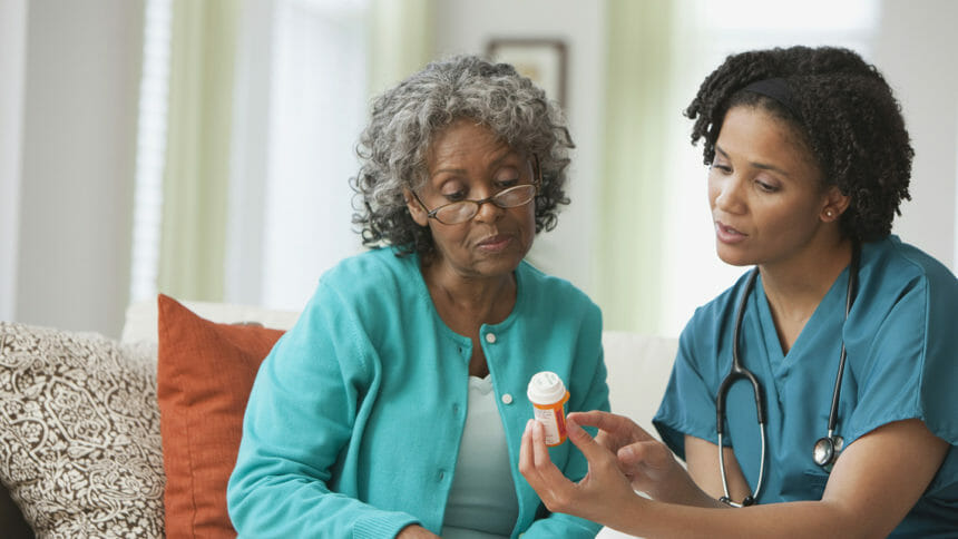 Home health worker explains drug instructions to senior at home.