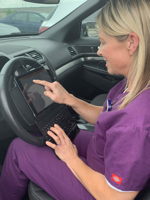 Caregiver in her car uses electronic health technology with a voice-to-text feature.