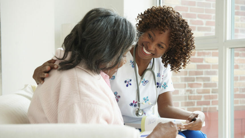 Home health nurse looks lovingly at senior while they look at book