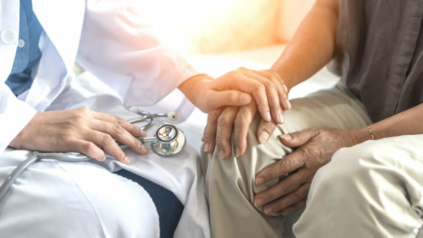 Medical person places hand on patient in gesture of reassurance