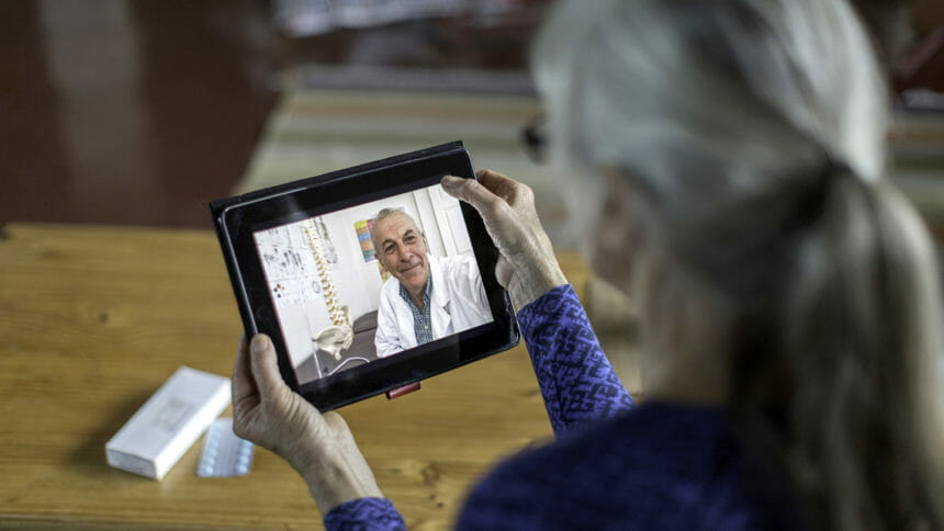 Older woman talks to doctor through tablet