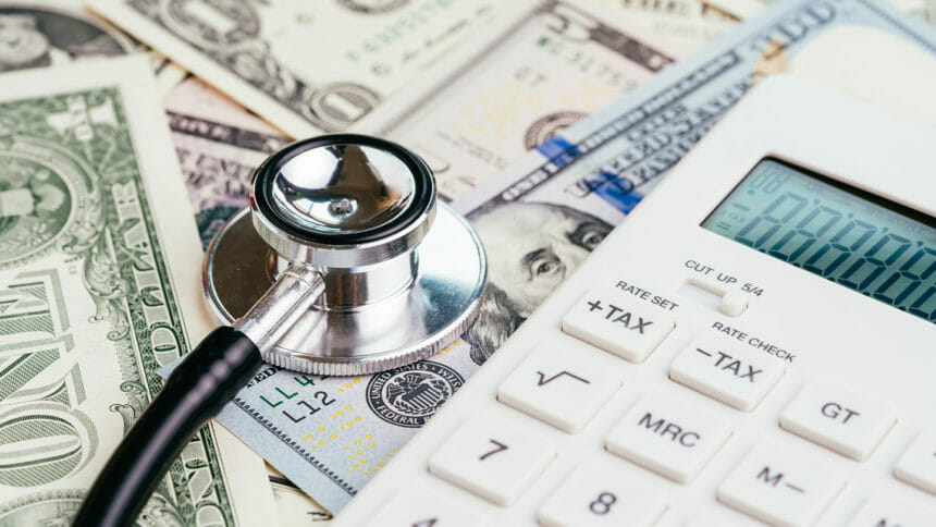 Image of stethoscope on money next to a calculator