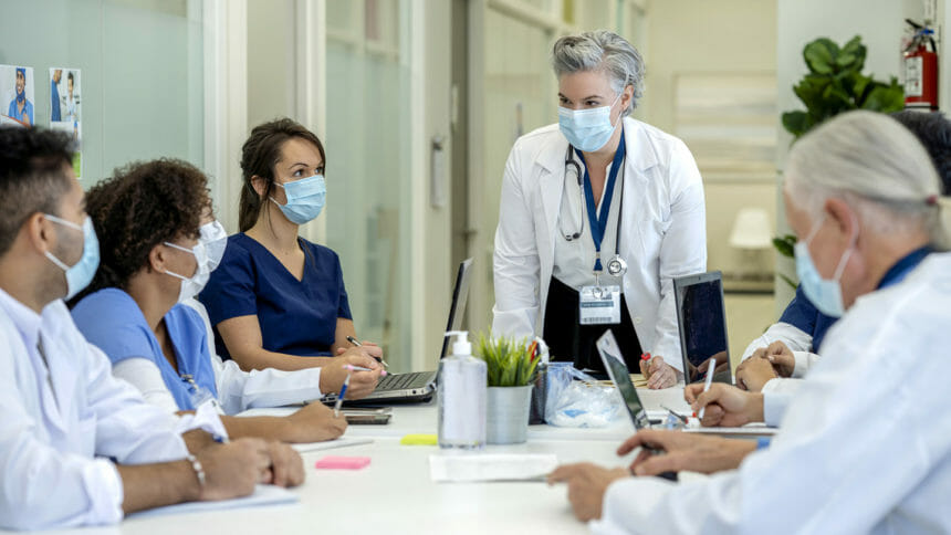 Clinicians wearing masks gather around a table