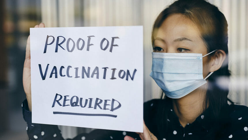 A business owner putting up a sign requiring proof of vaccination