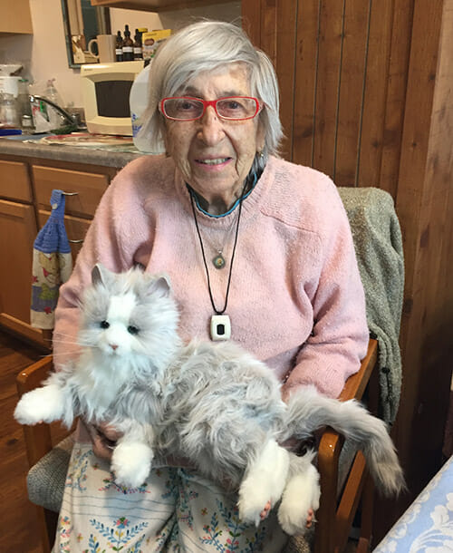 Elderly woman holding robotic cat