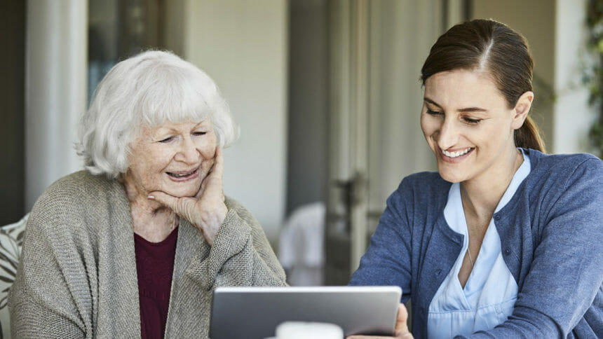 care workers helping older woman with laptop