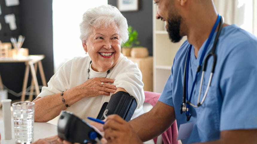 male caregiver checking senior's blood pressure
