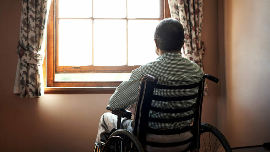 senior man in wheelchair looking out window