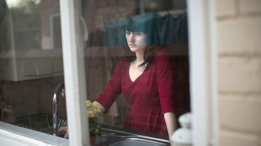 Looking at sad-looking woman is in front of sink through window
