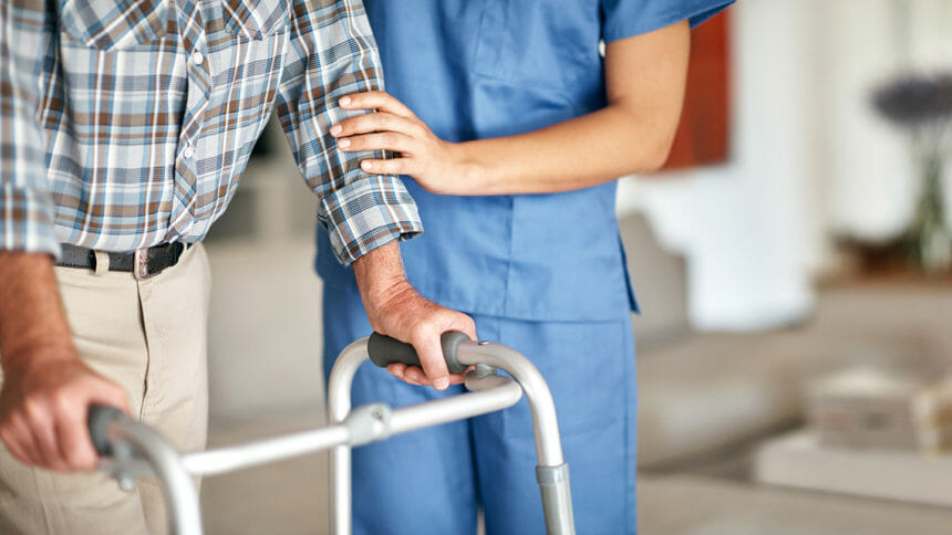 Shot of a woman assisting her elderly patient who's using a walker for support