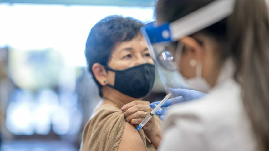 A woman raises her sleeve to receive an injection from a doctor at the pharmacy.