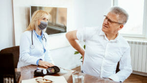 Middle-aged man being examined by a female doctor in a doctor's office. Patient complains to the doctor of kidney pain.