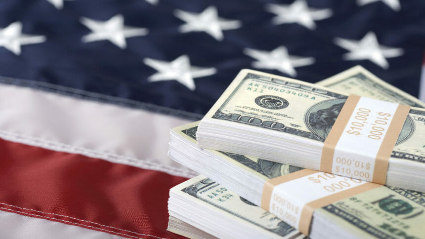 Macro shot of bundles of new $100 bills on US flag. Selective focus on the money.