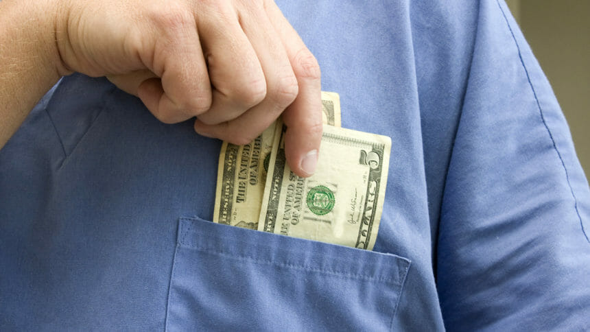 Doctor placing money in his pocket