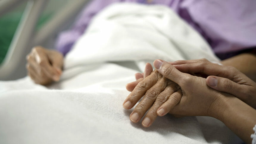 Image of daughter holding the mother's hand and encourage while her mother sitting on bed in AHCAH hospital