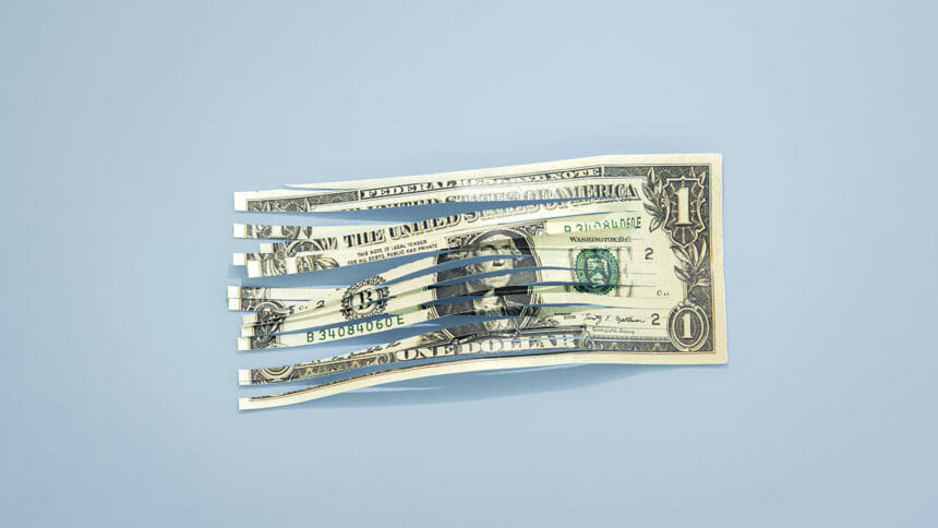 Conceptual image of a shredded one dollar bill with a colored background