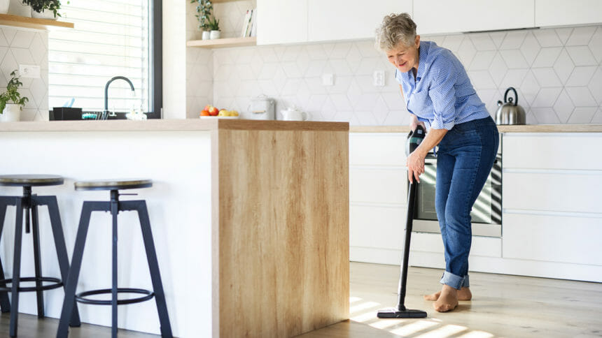 An old woman doing housework, hoovering.