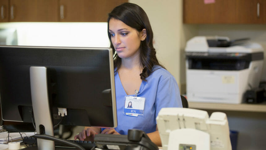 A nurse works at a computer