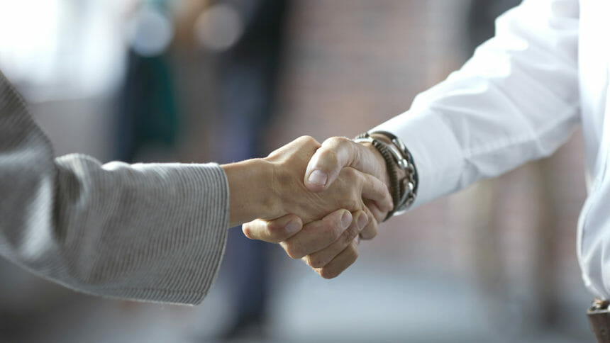 Close-up of businessman & businesswoman making handshake at convention