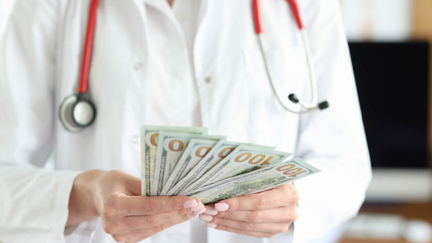 Doctor holds cash dollar bills in his hands. Medical service fee concept