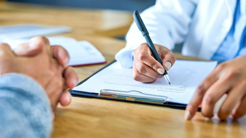 Closeup shot of a physician writing notes during a consultation with a patient
