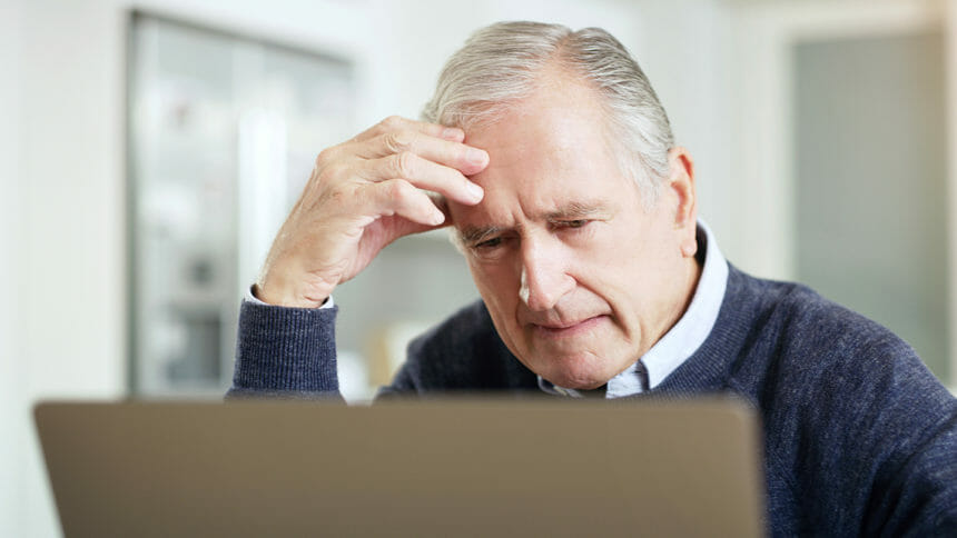 Shot of a senior man looking confused while using a laptop at home