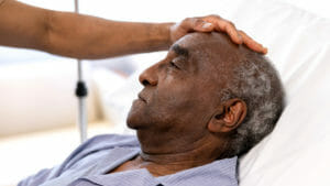 Close-up on a sick senior adult being visited at the hospital by his son - healthcare and medicine