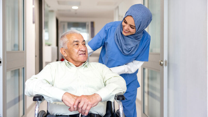 Muslim nurse with man in wheelchair