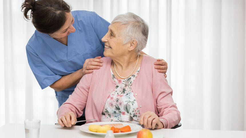Nurse greets senior eating nutritious meal