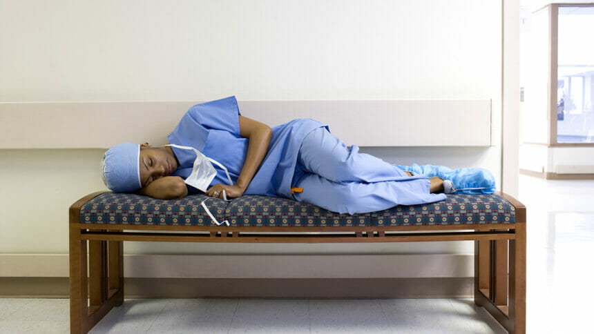A surgeon naps on a hospital bench.