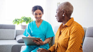 Caregiver speaks with elderly home care HCBS patient