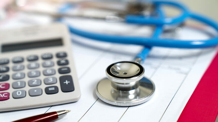 Cost of health care wages concept, stethoscope and calculator on document