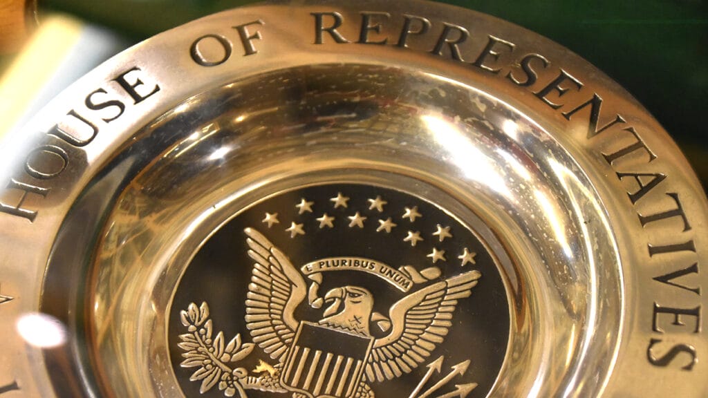 A metal disk bearing the name and seal of the House of Representatives.