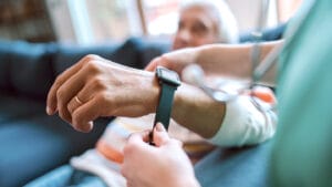 Caregiver puts smartwatch on man's wrist.