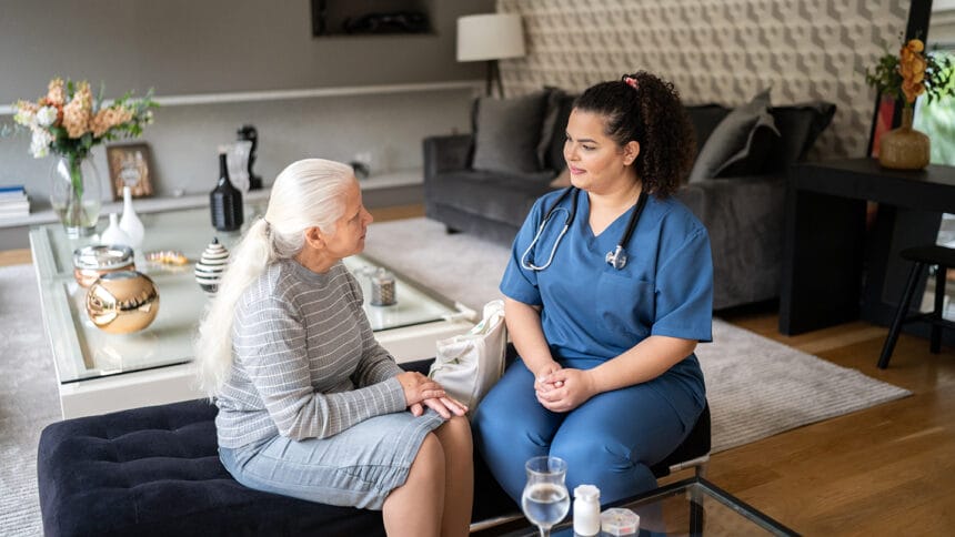 Home caregiver talking to senior patient at home
