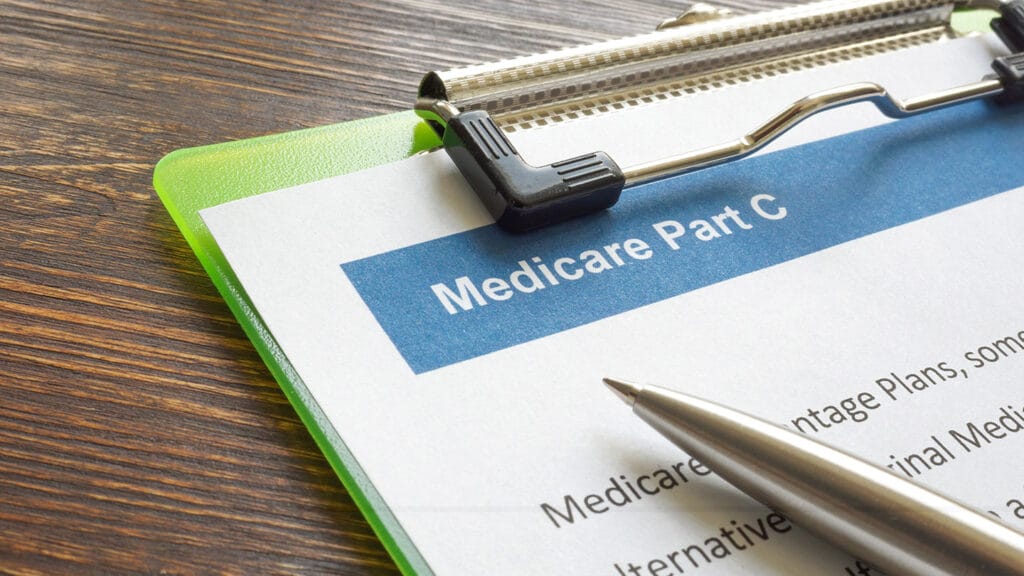 Medicare part C Medicare Advantage (MA) insurance papers with clipboard and pen.